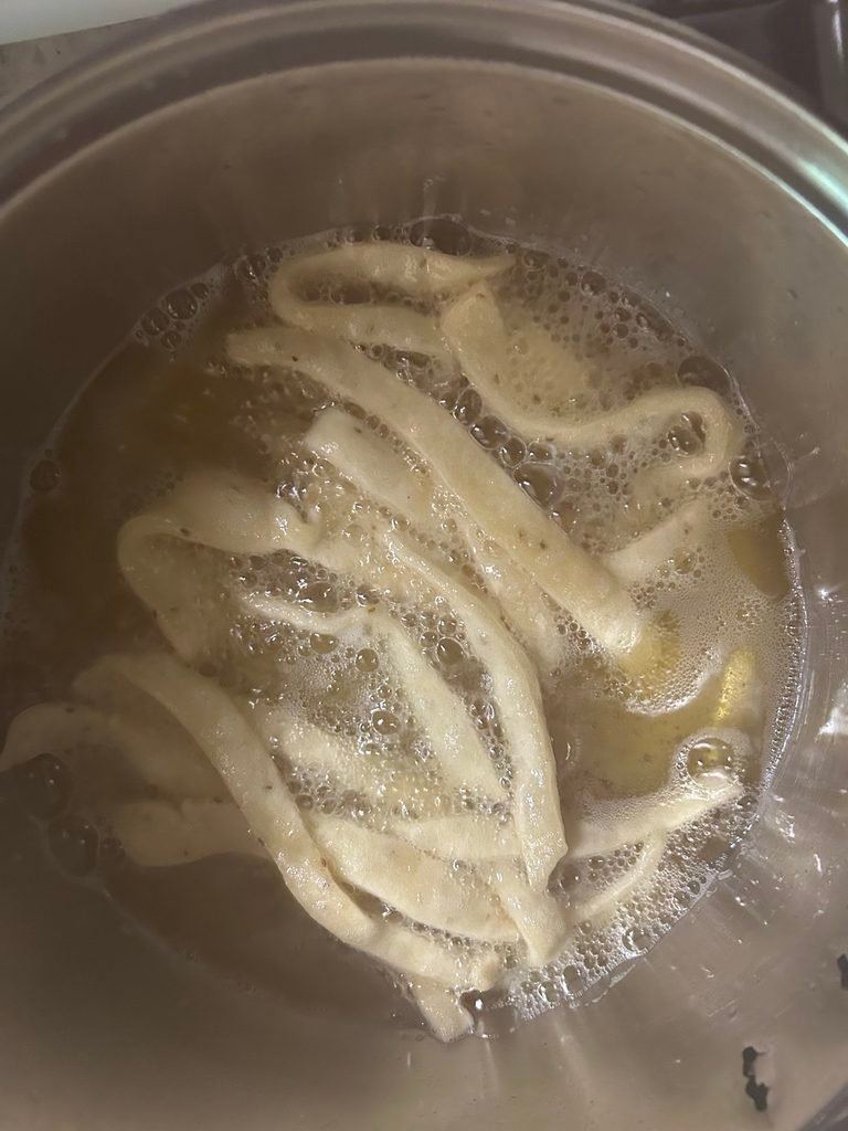 Namak pare strips frying slowly in oil until crisp and golden