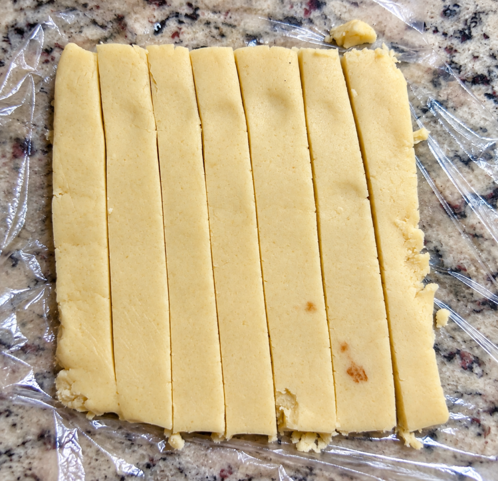 Vanilla and chocolate cookie dough cut into even strips for checkerboard cookies