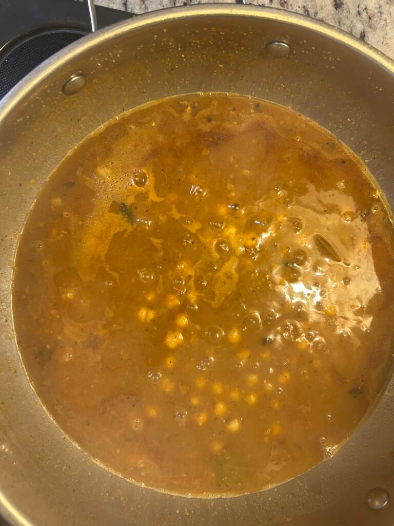 Chole simmering in gravy after adding cooked chickpeas