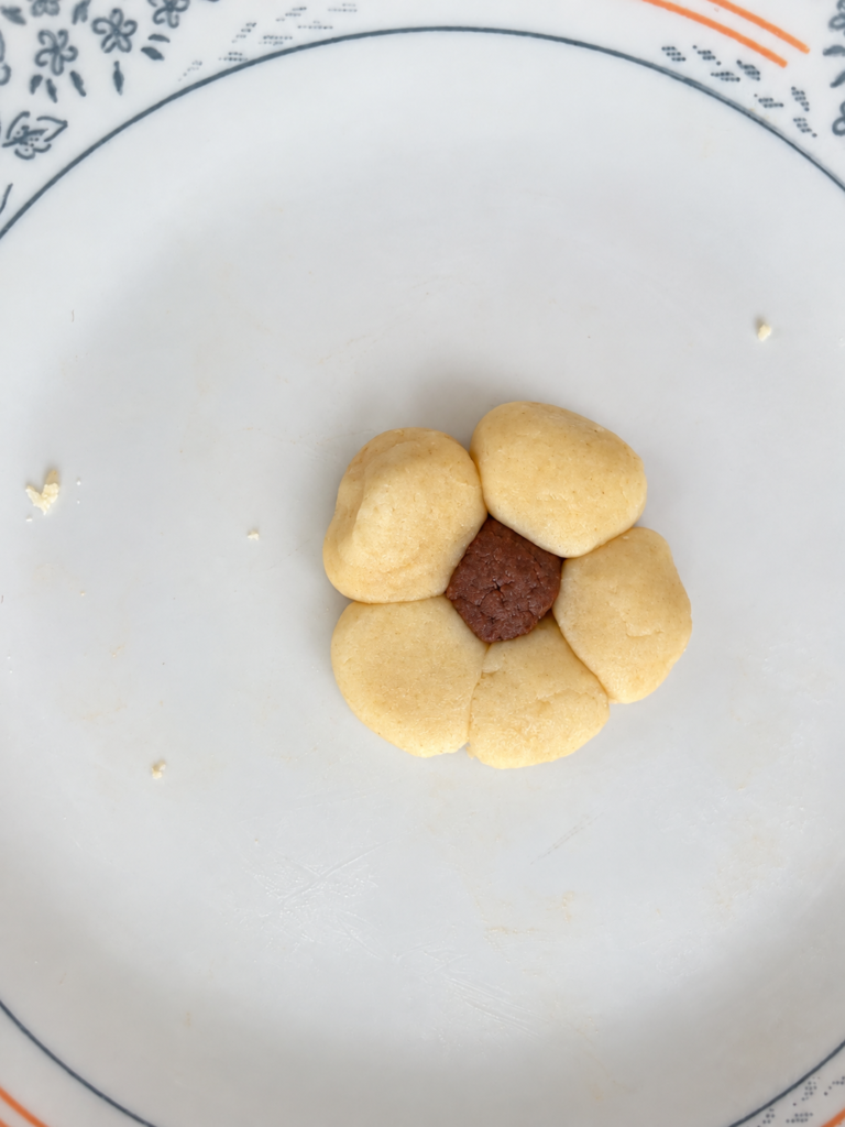 Vanilla dough balls arranged around a chocolate dough center to make a flower cookie