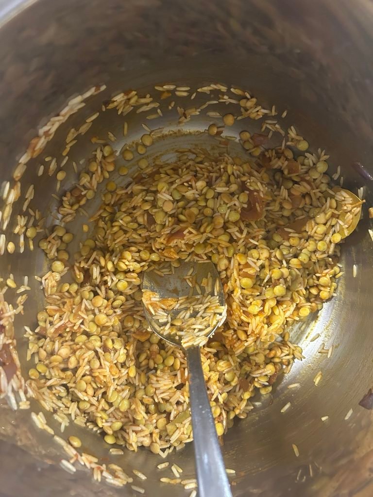 Soaked black masoor dal and rice mixed with spices and water before pressure cooking.