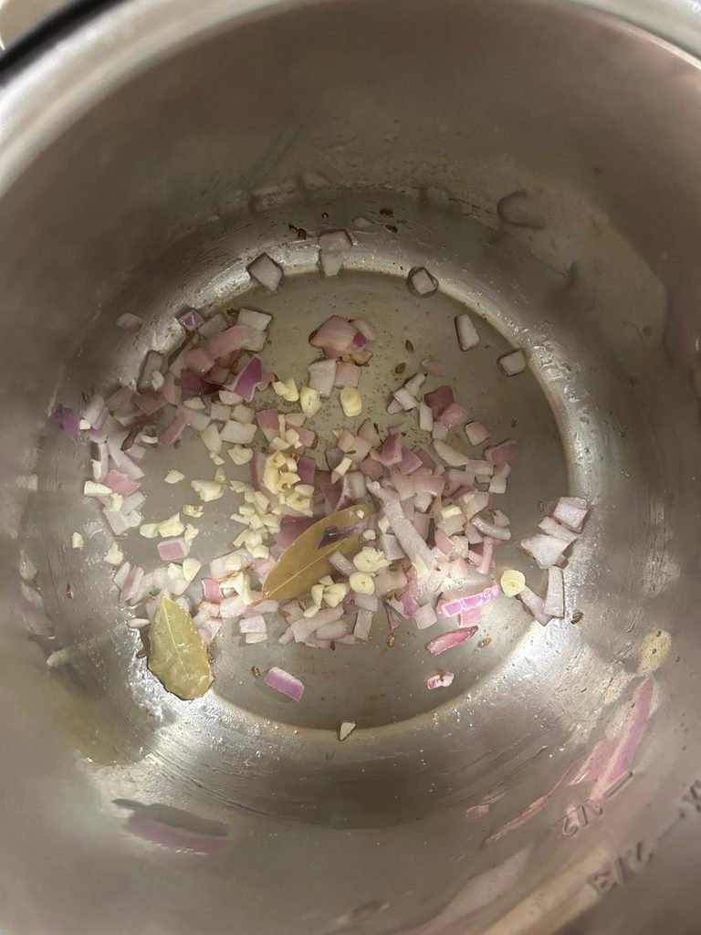 Onions, garlic, cumin, and whole spices sautéing in the Instant Pot.