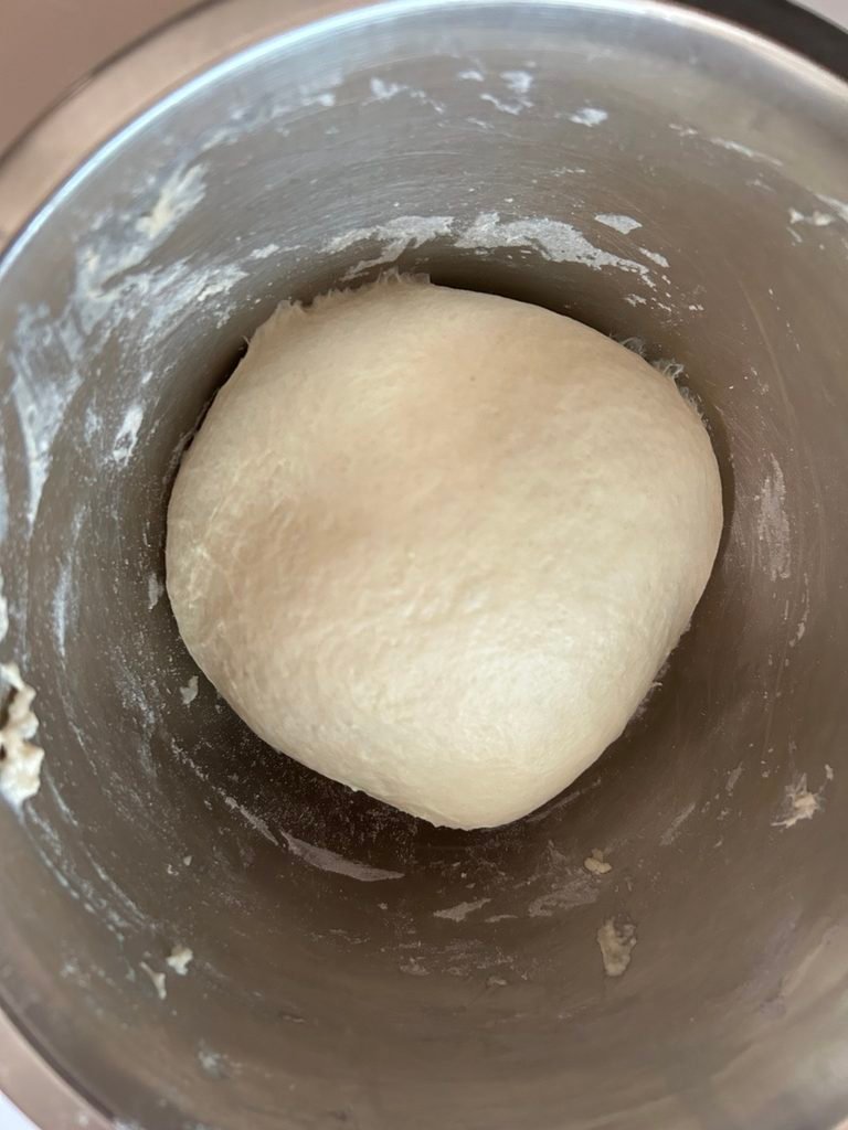Smooth and soft homemade bread dough resting in a stainless steel mixing bowl after kneading.